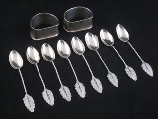 A pair of silver napkin rings and 8 Eastern white metal teaspoons