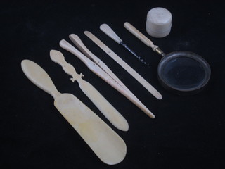 An ivory shoe horn, 2 ivory paper knives, pair of ivory glove stretchers, rouge pot, magnifying glass with ivory handle and a  scent bottle corkscrew