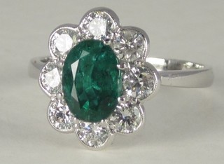 An 18ct white gold dress ring set an oval cut emerald surrounded  by diamonds, approx 0.80/1.15ct