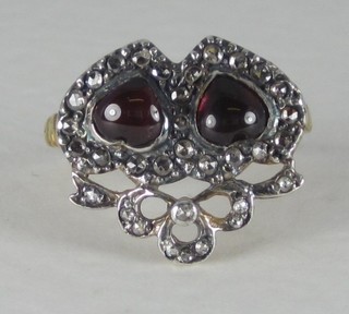 An 18ct yellow gold dress ring set entwined hearts set cabouchon cut garnets supported by diamonds