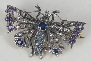 A gold brooch in the form of a butterfly set aquamarine, rubies, peridot, amethyst and diamonds