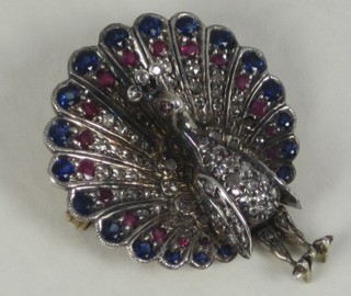 A gold brooch in the form of a peacock set diamonds, sapphires  and other stones