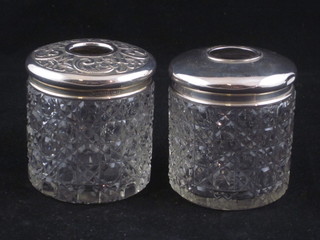 A pair of cylindrical cut glass hair tidies with silver lids 3"
