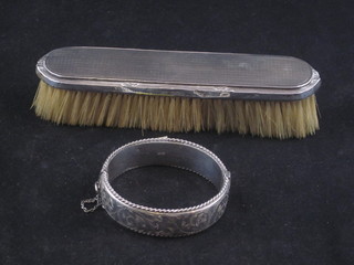 A silver backed clothes brush and a silver bangle