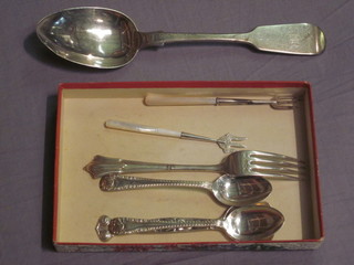 A silver fiddle pattern table spoon, 2 silver teaspoons, a silver fork, a silver caddy spoon and 2 silver handled pickle forks with  mother of pearl handles, 6 ozs