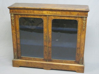 A Victorian inlaid figured walnut display cabinet, the interior fitted shelves enclosed by arch shaped panelled doors with gilt  metal mounts throughout, 46"  ILLUSTRATED