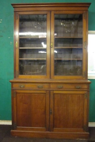 A Victorian walnut bookcase, the upper section with moulded cornice the base fitted 2 drawers above a double cupboard  enclosed by panelled doors, raised on a platform base 53"