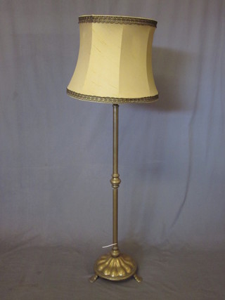 A brass adjustable standard lamp, raised on a circular foot with 3 scroll feet