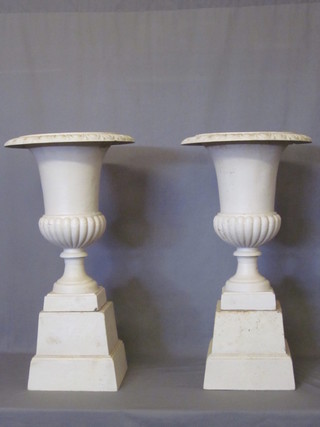A pair of Victorian style cast iron garden urns of trumpet form with egg and dart borders, raised on square bases 17"