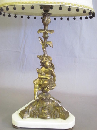 A gilt metal table lamp in the form of a seated cherub, raised on  a white triangular marble base 20"