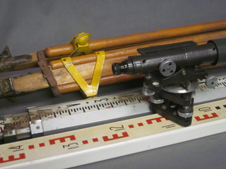 A surveyors dumpy level contained in a leathered oak case  together with a tripod and 2 ranging rods