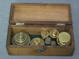 A rectangular mahogany box with hinged lid containing various brass weights