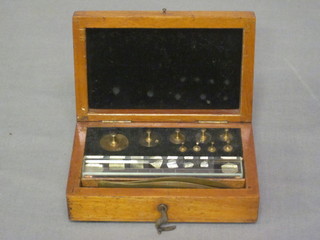 A rectangular mahogany box with hinged lid containing a  collection of various weights