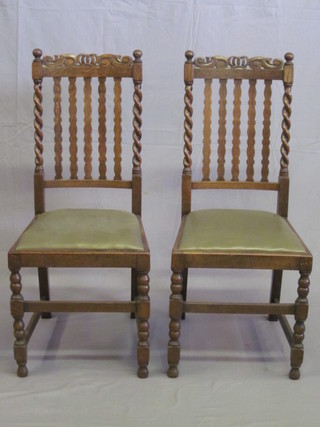 A pair of 1930's carved oak bar and stick back dining chairs with spiral turned decoration and upholstered drop in seats, raised on  turned and block supports