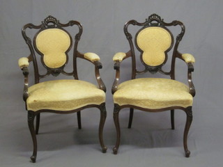A pair of Victorian carved walnut open arm chairs with  upholstered seats and backs, the seats of serpentine outline, raised  on cabriole supports