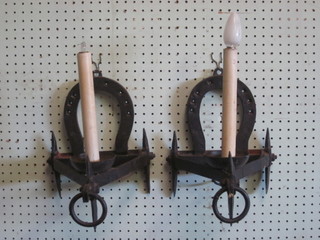 A pair of iron wall light brackets with horse shoe decoration