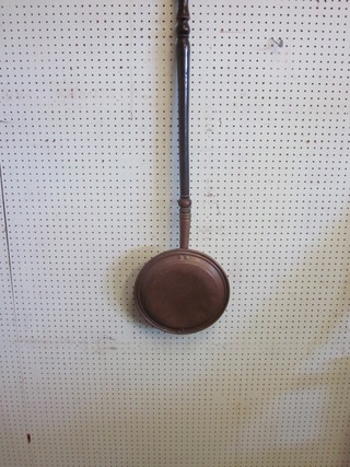 A copper warming pan with turned ebony handle