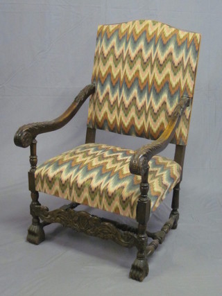 A Carolean style carved oak open arm chair, the seat and back upholstered in tapestry material, raised on turned and block  supports