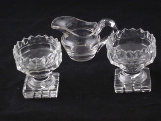 A pair of circular 19th Century cut glass salts raised on square  feet 3" and a 19th Century glass jug 2", chip to rim,