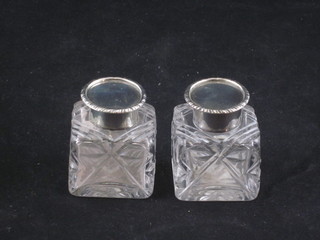 A pair of Victorian square cut glass inkwells with silver lids,  London 1898 and 1900, 1 1/2"