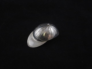 A white metal caddy spoon in the form of a jockey's cap