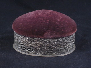 An Edwardian oval pierced white metal trinket box with floral decoration, the lid set a pin cushion 5"