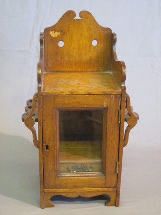 A Victorian honey oak cabinet enclosed by glazed panelled door, the sides fitted pipe racks 7"