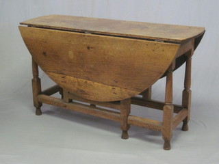 An 18th Century honey oak oval drop flap gateleg dining table, fitted a drawer and raised on turned and block supports 51"