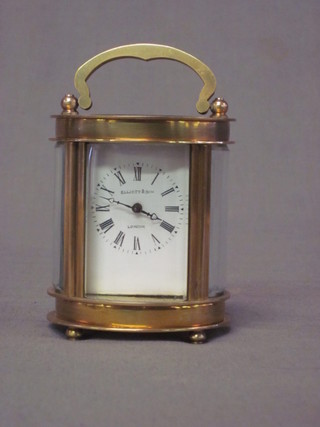 An oval shaped miniature carriage clock with enamelled dial and Roman numerals by Elliott & Sons, contained in a gilt metal case