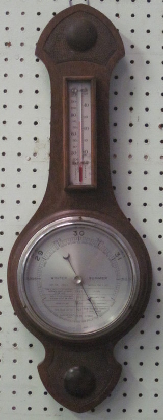 An aneroid barometer and thermometer with silvered dial  contained in an oak wheel case