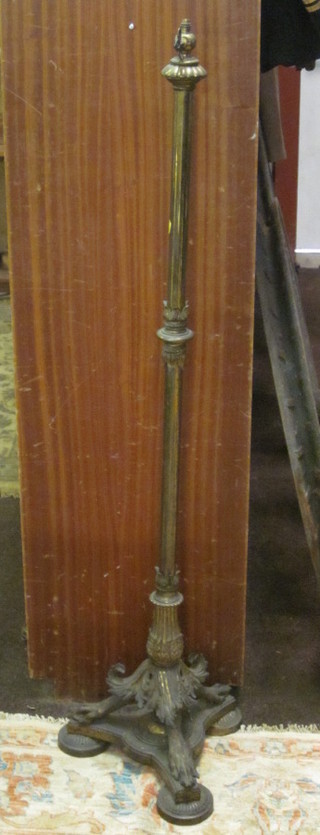 A Victorian brass standard lamp with triform and paw base
