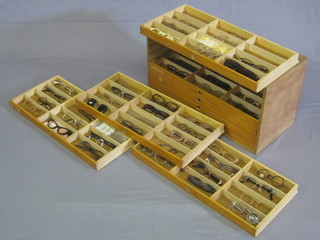 A shallow plywood chest of 8 long drawers containing various vintage spectacles