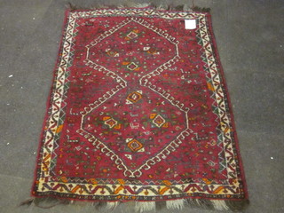 A red ground Persian rug with 2 medallions to the centre 64" x  36"