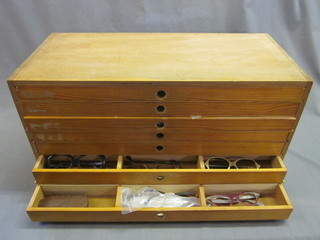 A plywood chest fitted 7 shallow drawers containing various vintage spectacles