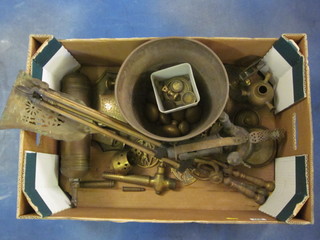 A cardboard box containing a collection of horse brasses, door knobs, brass hand fire extinguisher etc