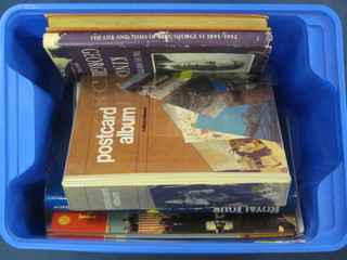 A collection of coloured postcards together with a quantity of  various books contained in a blue plastic crate