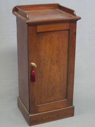 A Victorian mahogany pot cupboard with three-quarter gallery enclosed by a panelled door, raised on a platform base 18"