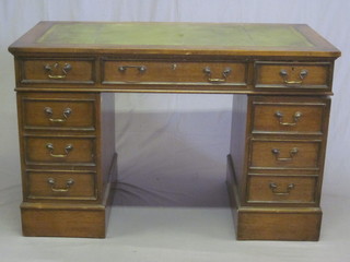 An oak kneehole pedestal desk with green inset writing surface  above 1 long and 3 short drawers 48"