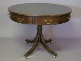 A circular Georgian style mahogany drum table with green inset tooled leather writing surface, fitted 4 drawers, raised on a turned  column ending in brass caps castors 44"