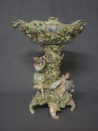 A 19th Century German porcelain table centre piece comprising  oval pierced basket raised on a pedestal supported by figures 15"
