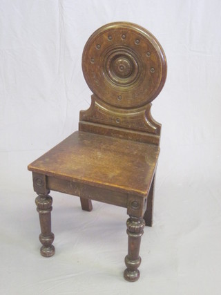 A pair of Victorian carved oak hall chairs with solid seats and backs