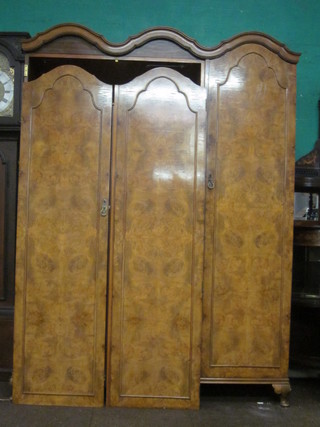 A Queen Anne style walnut triple wardrobe with wavy shaped cornice enclosed by 3 arch shaped panelled doors, raised on  cabriole supports, 60"