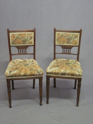 A pair of Edwardian carved walnut dining chairs with  upholstered seats and backs and bobbing turned decoration, raised  on turned supports by Shoolbred