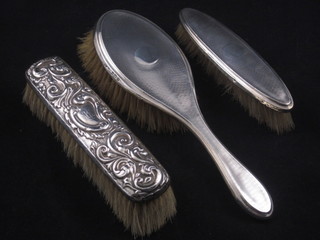 A silver backed hair brush and 2 clothes brushes
