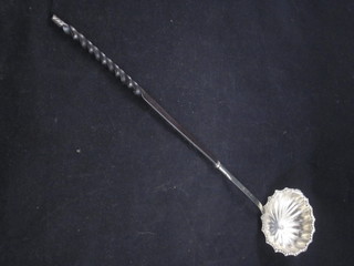 A white metal scallop shaped ladle with whalebone twist handle