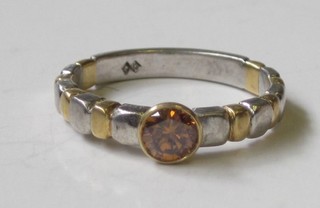 A bi-metal ring set a circular yellow cut stone