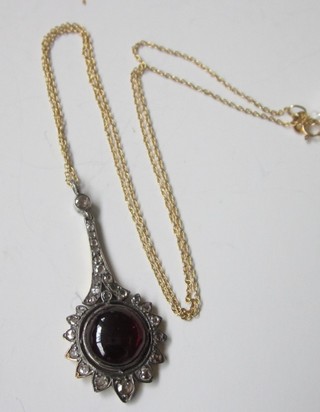 A fine gold chain hung a pendant set a cabouchon cut garnet  surrounded by diamonds