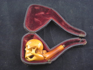 A carved cheroot holder in the form of a skull being clasped by a  hand