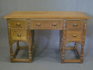 A carved oak writing table fitted 1 long and 4 short drawers with arcaded decoration, raised on turned and block supports 46"