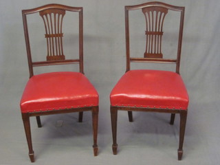 A set of 6 Edwardian mahogany Hepplewhite style dining chairs with pierced vase shaped slat backs and upholstered seats raised  on square tapering supports ending in spade feet